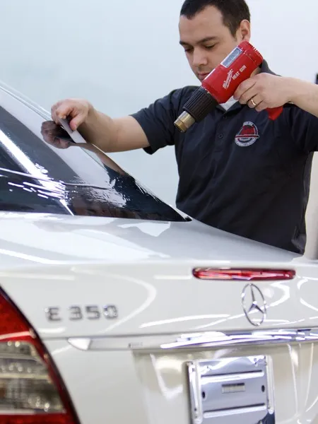 Technician applying window tint film to a vehicle's rear windshield