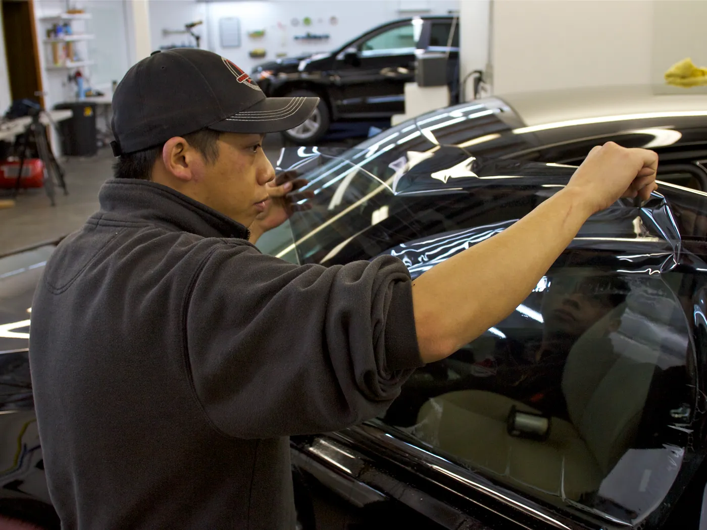 Technician applying window tint film to a vehicle's exterior glass