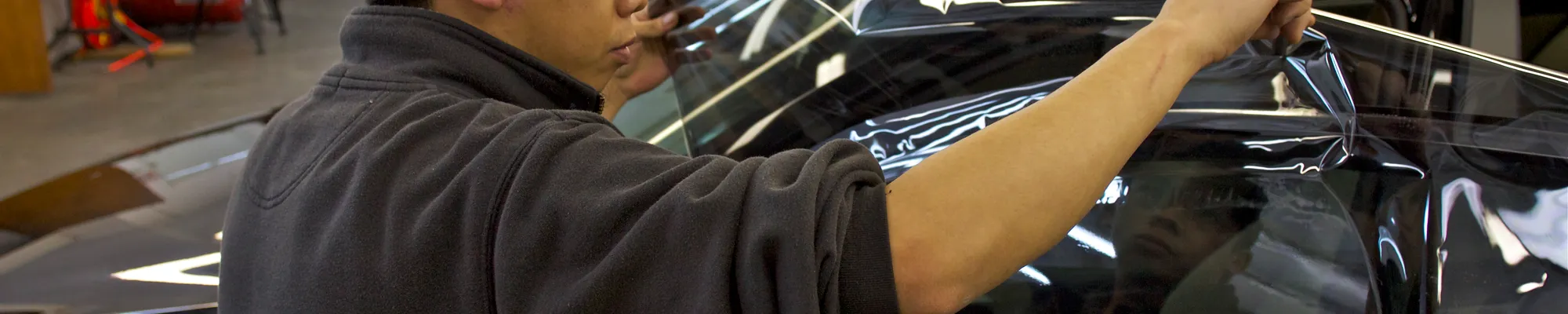 Technician applying window tint film to a vehicle's exterior glass