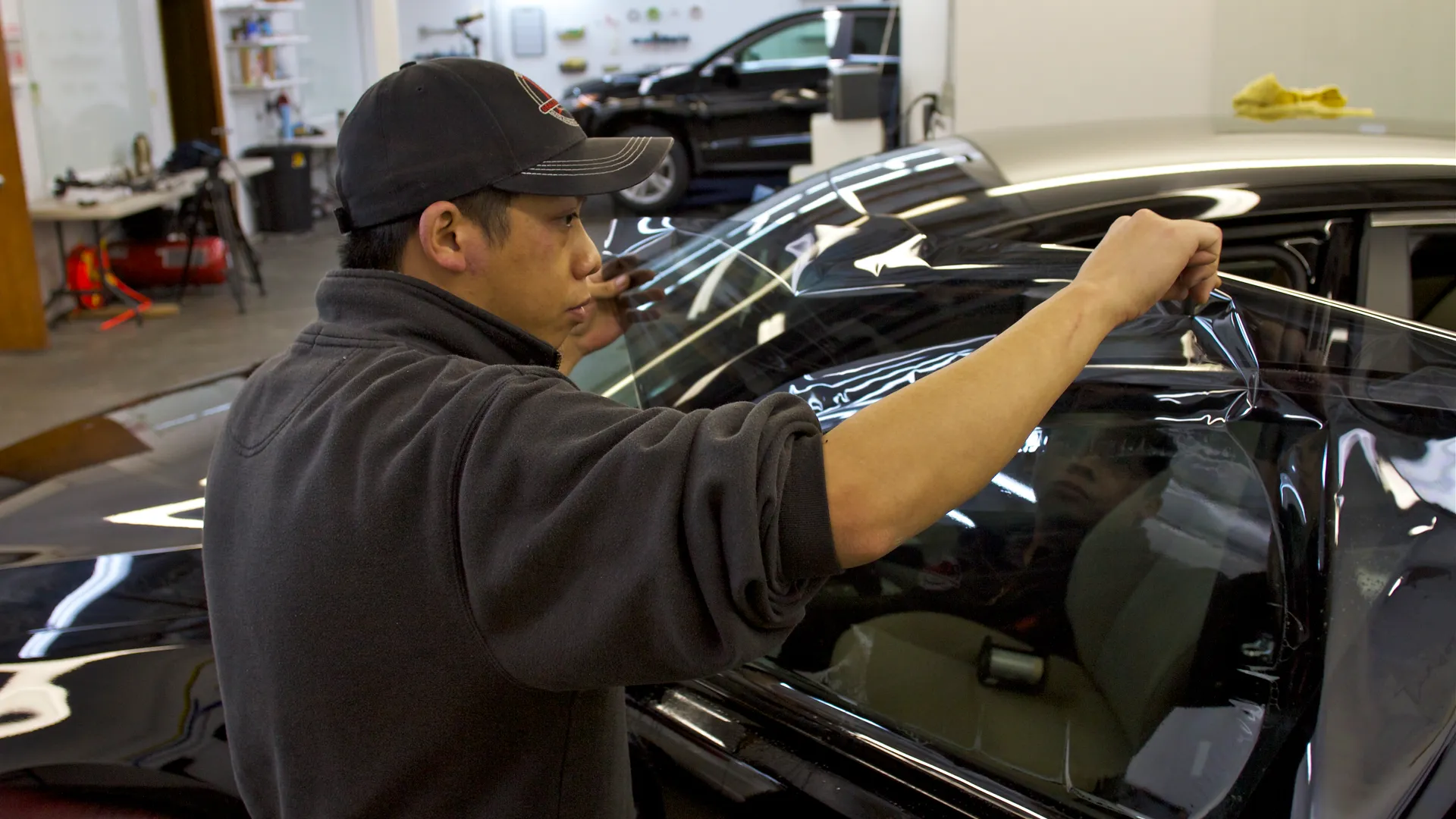 Technician applying window tint film to a vehicle's exterior glass
