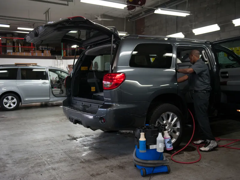 Technician cleaning the interior of an SUV with the rear hatch open