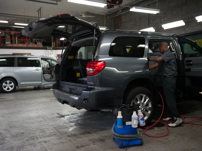 Technician cleaning the interior of an SUV with the rear hatch open