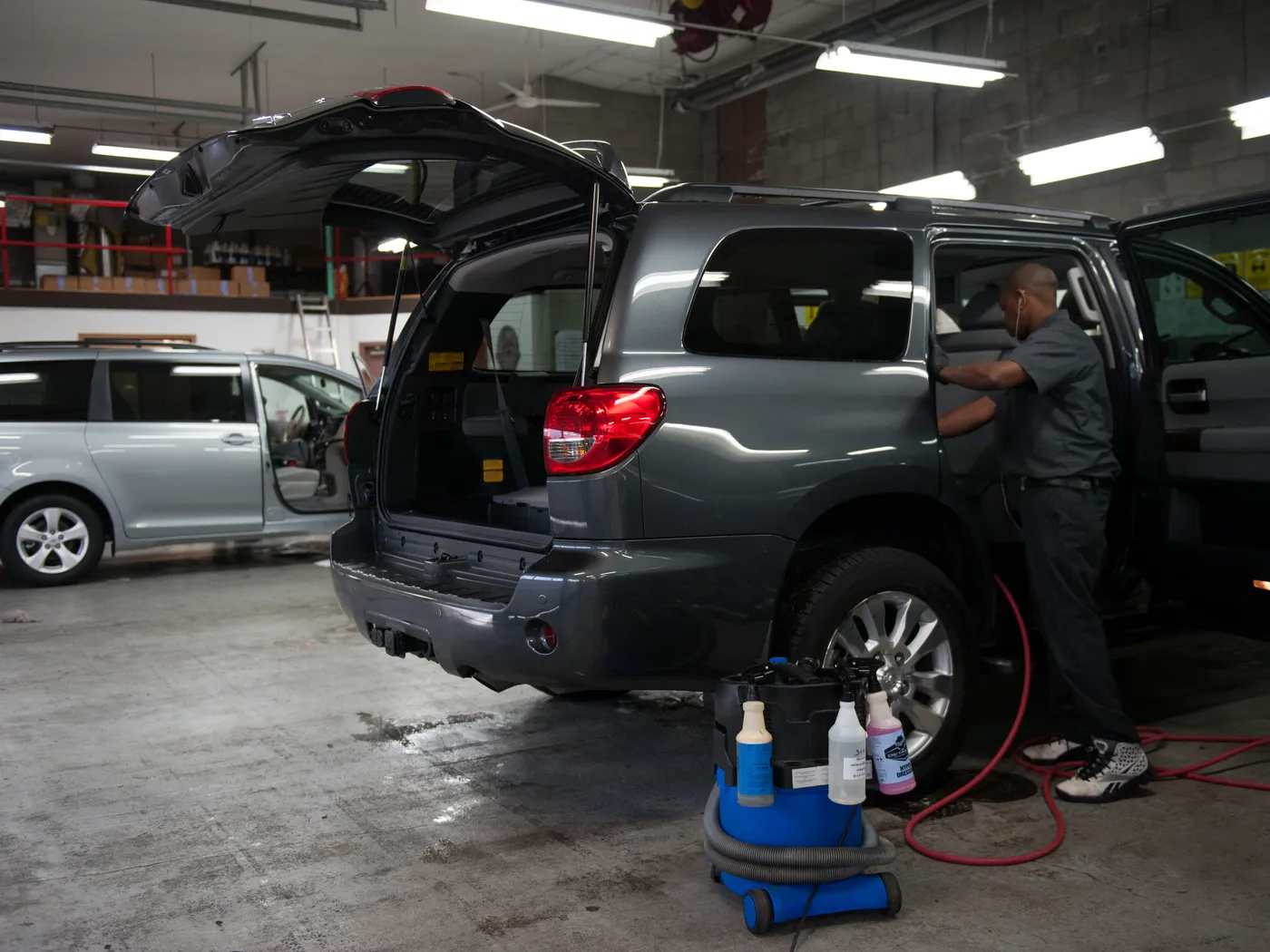 Technician cleaning the interior of an SUV with the rear hatch open